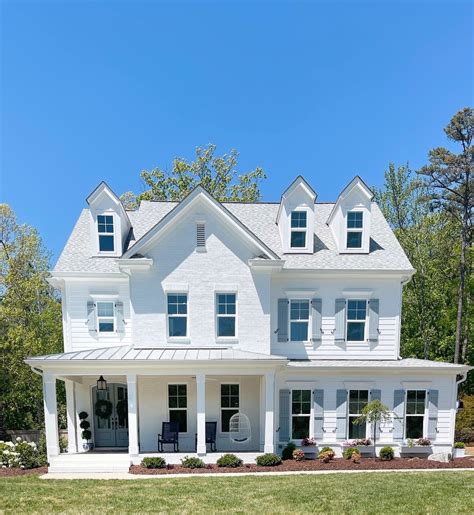 white house with blue metal roof|white cottage with blue shutters.